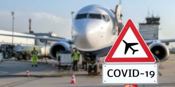 Airplane at the airport with a coronavirus sign in the foreground [Covid-19, travel, planes]
