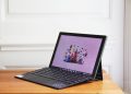 The Asus Chromebook Detachable CM3 open, angled to the left. The screen displays a cartoon city scene on a pink background.