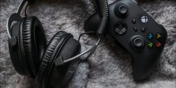 An Xbox Series X controller on shaggy carpet next to a wireless headset