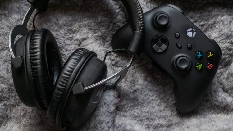 An Xbox Series X controller on shaggy carpet next to a wireless headset