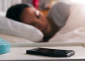 A woman sleeping next to her phone.