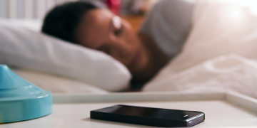 A woman sleeping next to her phone.