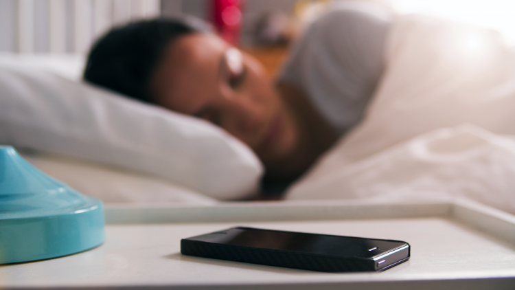 A woman sleeping next to her phone.