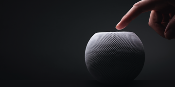 Someone touching an Apple HomePod Mini.