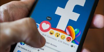 Closeup of a person selecting the "Love" reaction to a post on the Facebook mobile app.