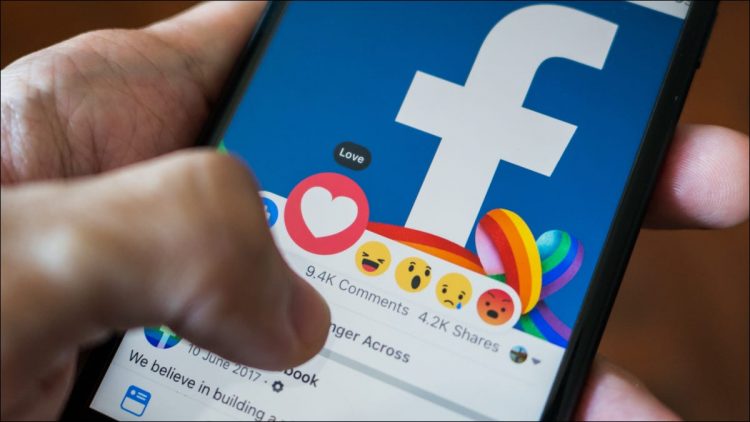 Closeup of a person selecting the "Love" reaction to a post on the Facebook mobile app.