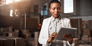 A manager uses a tablet in a warehouse / industrial environment.