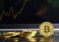 Bitcoins coin on keyboard with market price chart