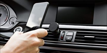 A person docking their phone on a magnetic in-car phone dock.