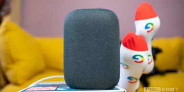 Google Nest Audio in gray on top of book in front of yellow couch.