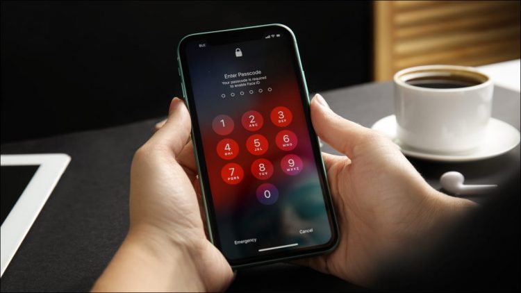 Hands entering the passcode on an iPhone 11 lock screen.