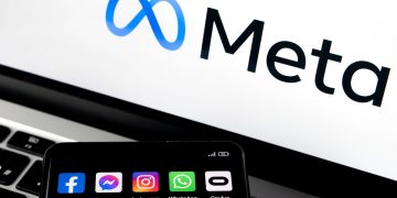 Silhouette of smartphone with Facebook, Messenger, whatsApp, Instagram, Oculus apps and blurred META logo on background.