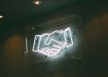 Neon sign > handshake / deal / agreement / partnership / team / merger