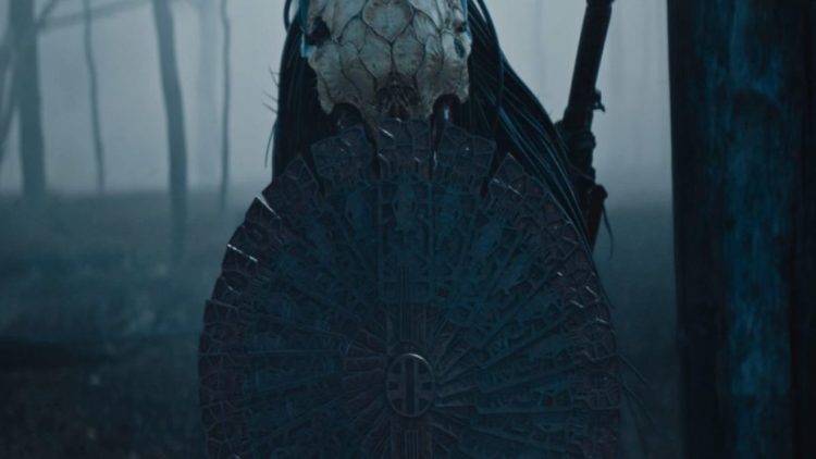 Dane DiLiegro as The Predator with a shield in the forest in Prey