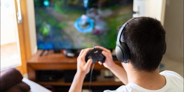 Someone playing a video game while wearing wireless headphones.