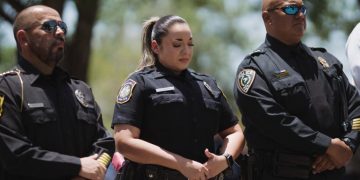 A Uvalde police department officer, standing next to Uvalde CISD police chief Pete Arredondo, reacts during a press conference in Uvalde, Texas.