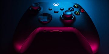 Closeup of a carbon black Xbox Series S controller in blue and red lighting.