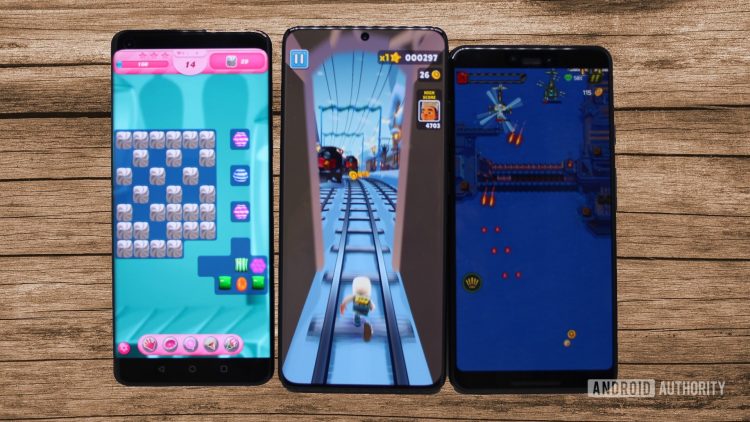Three Android phones running three games with a wood panel background