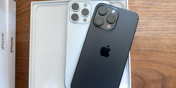 iPhone 14 Pro in Space Black and iPhone 14 Pro in Silver on a wood desk