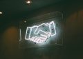 Neon sign > handshake / deal / agreement / partnership / team / merger