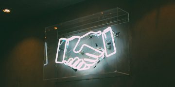 Neon sign > handshake / deal / agreement / partnership / team / merger