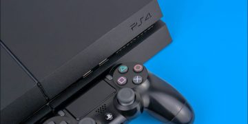 A Sony PS4 console with a DualShock controller next to it on a blue background.