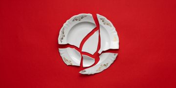 Broken white plate on red background