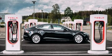 Tesla Model S parked next to a line of Superchargers