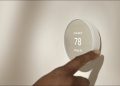 Someone adjusting a smart thermostat.