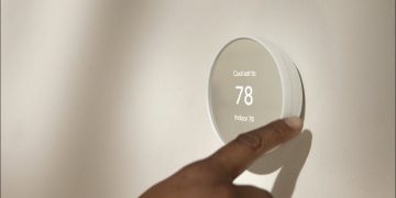Someone adjusting a smart thermostat.