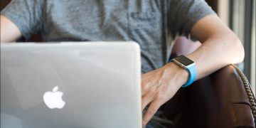 Man using a MacBook while wearing an Apple Watch