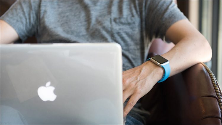 Man using a MacBook while wearing an Apple Watch