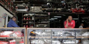 Salesmen wait for customers at a secondhand car parts warehouse, with car parts behind them and on display in the counter, in the industrial area of the capital Nairobi, Kenya