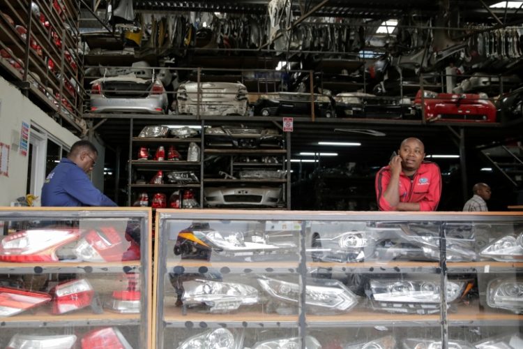 Salesmen wait for customers at a secondhand car parts warehouse, with car parts behind them and on display in the counter, in the industrial area of the capital Nairobi, Kenya