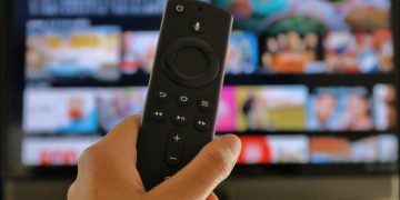 Closeup of an Amazon Fire TV Stick remote in front of a television screen.