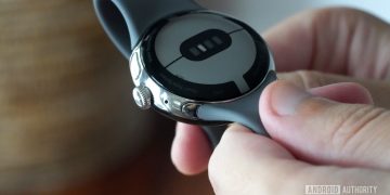 A user holds their Google Pixel Watch in hand illustrating how to find the band removal button.