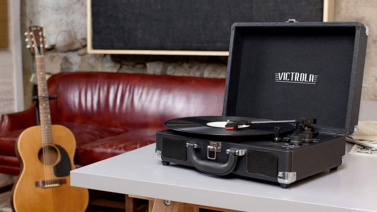 A Victrola record player next to a guitar