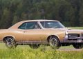 A 1967 Pontiac Tempest GTO drives down a country road.
