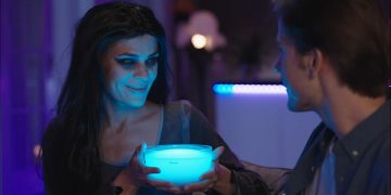 A woman dressed up as a vampire, holding a Govee portable smart light.