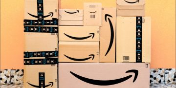 Amazon boxes piled in front of a yellow wall