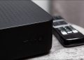 A black cable box sits on a table.