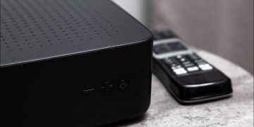 A black cable box sits on a table.