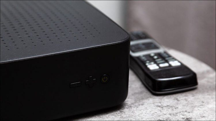 A black cable box sits on a table.
