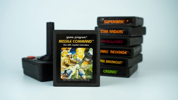 Missile Command video game cartridge standing next to a classic Atari controller and a stack of other games.