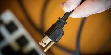 A man unplugging a device to save money.
