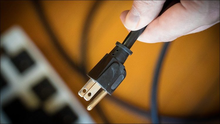 A man unplugging a device to save money.