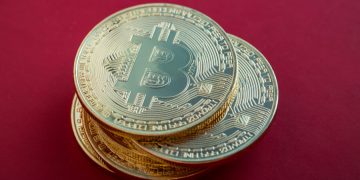 Pile of Bitcoins on red background.