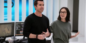 Rob McElhenney and Charlotte Nicdao standing in front of a desk in Mythic Quest Season 3.