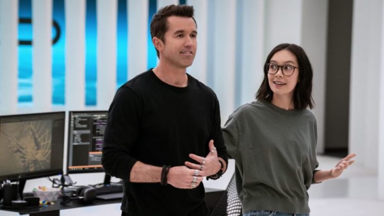 Rob McElhenney and Charlotte Nicdao standing in front of a desk in Mythic Quest Season 3.