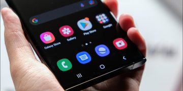 A man holding a Samsung phone with apps displayed